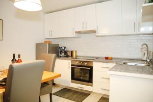 a kitchen with white cabinets and a wooden table at Apartman Incerum in Požega
