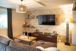 a living room with a couch and a tv on a brick wall at Apartman Incerum in Požega