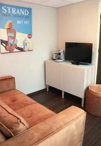 a living room with a couch and a flat screen tv at Boutique hotel Zeelui in Egmond aan Zee
