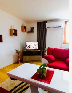 a living room with a red couch and a tv at Apartman 053 in Doboj