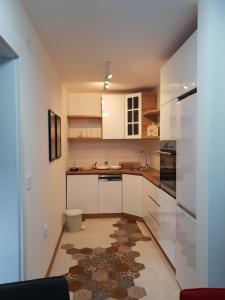 a kitchen with white cabinets and a rug on the floor at Alo Alo Apartman 5 in Kruševac