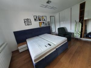 a bedroom with a large bed and a chair at Alo Alo Apartman 5 in Kruševac