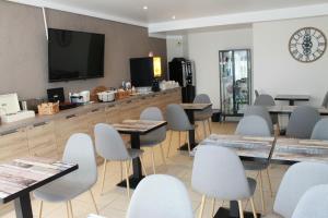 a waiting room with tables and chairs and a flat screen tv at Libre Hôtel in La Vespière