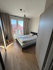 a bedroom with a bed and a large window at Apartament Skarbowa East in Leszno