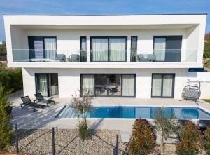 a house with a swimming pool in front of it at Villa Sensei in Linardići