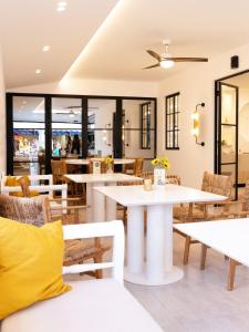 a restaurant with white tables and chairs and windows at Blue Sea Boutique Apartments in Olympic Beach