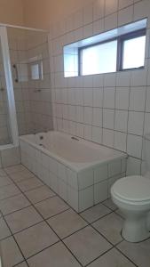 a white bathroom with a tub and a toilet at House with Those Stairs in Langebaan