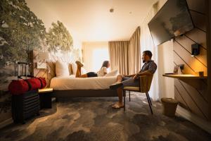 a man sitting in a chair in a hotel room at Bô Hôtels Ambronay in Ambronay