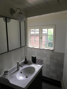 a white bathroom with a sink and a window at De Kleine Prins Enkhuizen in Enkhuizen