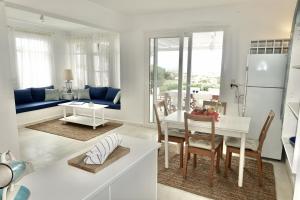 a kitchen and living room with a white table and chairs at Villa E - Kamari Village in Kastraki