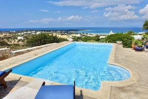 a swimming pool with a view of the ocean at Villa E - Kamari Village in Kastraki