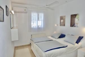 a white bedroom with two beds and a window at Villa E - Kamari Village in Kastraki