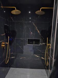 a bathroom with black marble walls and gold fixtures at Hollywood Spa Jacuzzi - Cinéma in Château-Thierry +27 photos