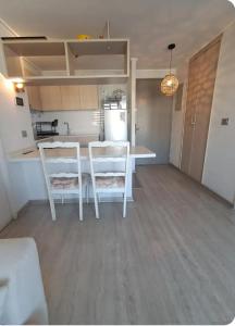a kitchen with two white chairs and a table at Plaza ñuñoa in Santiago