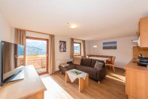 a living room with a couch and a tv and a table at Pension Bergbauernhof Irxner in Schladming