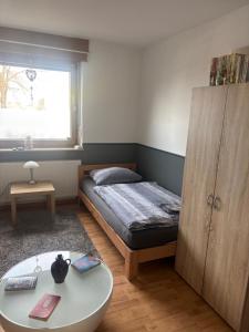 a small bedroom with a bed and a table at Palms Zimmer in Frechen
