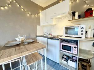 a kitchen with a microwave and a table with wine glasses at Vacances à la mer - studio in Calais +22 photos