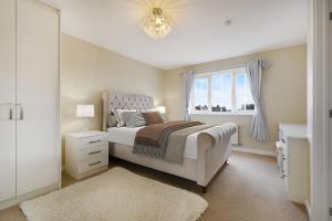 a white bedroom with a bed and a window at Folly Lodge in Barnsley