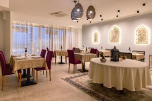 a dining room with tables and chairs and windows at Riviera Spa Resort - Adults Only in Mellieħa