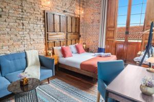 a room with a bed and chairs and a brick wall at Delgadillo Boutique Hotel by Socialtel in Bogotá