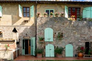 a building with green shutters and flowers on it at Agriturismo Vialto in Forcoli