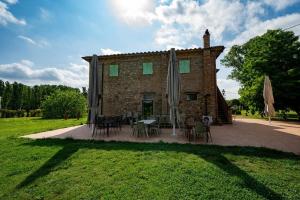 a building with a patio with tables and umbrellas at Agriturismo Vialto in Forcoli