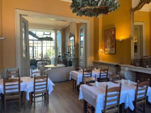 a restaurant with white tables and chairs and a fireplace at Hotel Ter Duinen in Bruges
