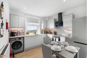 a kitchen with white cabinets and a table with chairs at Birdies Nest in Carnoustie