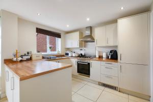 a kitchen with white cabinets and a wooden counter top at Folly Lodge in Barnsley