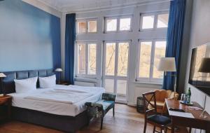 a bedroom with a bed and a desk and windows at Hotel Villa Viktoria Luise in Blankenburg