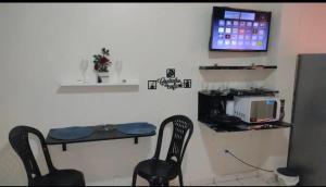 a room with two chairs and a table and a tv at Suíte panorama histórico in Manaus