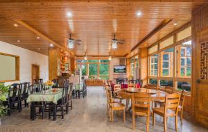 a dining room with tables and chairs and windows at Serenity Inn in Gaotian