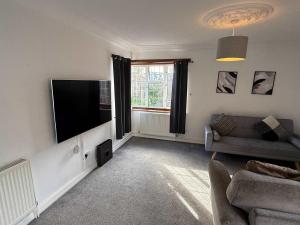 a living room with a couch and a flat screen tv at Large 4 Bed with Parking in Hillmorton