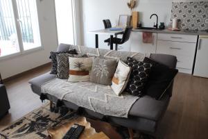 a couch with pillows on it in a living room at Gîte La Tchoupetta,proche Narbonne jaccuzi, jardin, canalplus, netflix in Peyriac-de-Mer