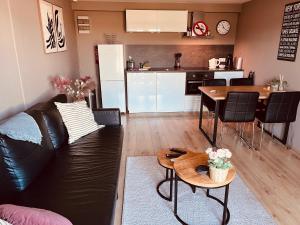 a living room with a black leather couch and a kitchen at B&B Pardoen in Poortugaal