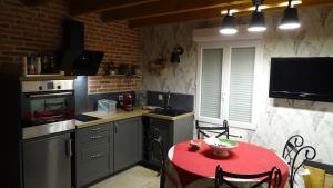 a kitchen with a red table and a kitchen with a red tableablish at Pigeonnier de campagne in Moncaut