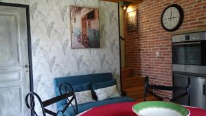 a living room with a blue couch and a clock on the wall at Pigeonnier de campagne in Moncaut