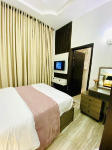 a bedroom with a bed and a desk and a mirror at Bumcy Apartment in Ankuru