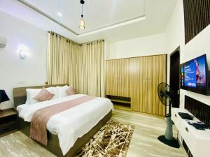 a bedroom with a bed and a flat screen tv at Bumcy Apartment in Ankuru