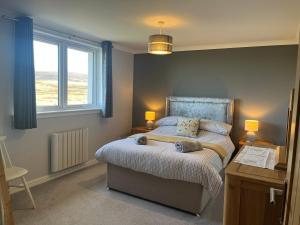 a bedroom with a bed and two lamps and a window at Buaile nan Carn in Kilmuir