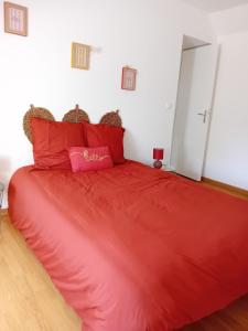 a red bed with red pillows in a room at Le gîte d'Elisa in Roullours