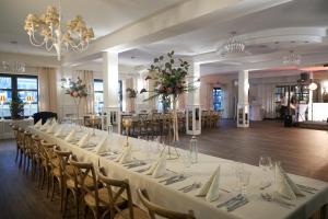 a long table with white tables and chairs in a room at Hotel NORD in Mierzyn