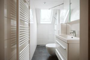 a white bathroom with a toilet and a sink at Jonkerstee 59 - Ouddorp in Ouddorp +17 photos