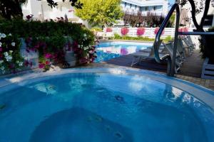 a large blue swimming pool with a slide at Hotel Riz in Cesenatico +37 photos