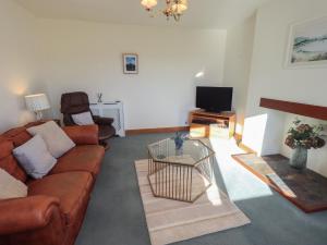 a living room with a couch and a tv at 2 Lupton Hall Cottages in Carnforth