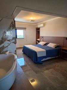 a bedroom with a bed and a bath tub at Optimum Plaza Hotel in Monte Alto
