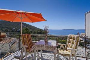 a table and two chairs with an umbrella on a balcony at Apartments Tasha in Štivan
