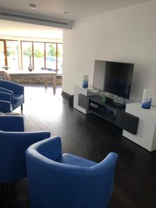 a living room with blue chairs and a flat screen tv at The Walnut Retreat Castlewellan in Ballyward
