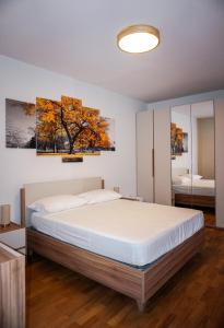 a bedroom with a bed and a tree on the wall at Colli Apartment Lake Como in Malgrate