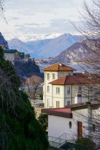 a large white building with mountains in the background at Colli Apartment Lake Como in Malgrate